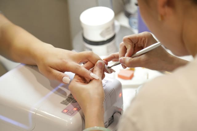 A Mai Lacquer technician shaping a client's nails at a clean manicure station
